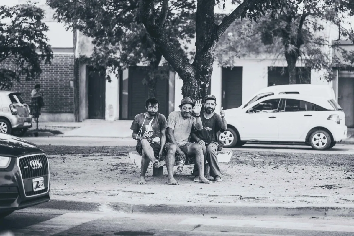 Tres amigos sentados en la vereda